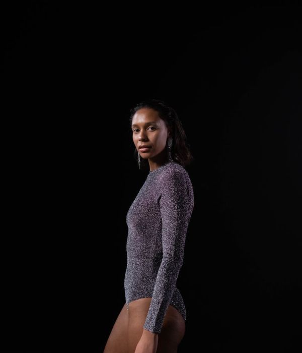 Athlete performing a challenging yoga pose in a dark studio.